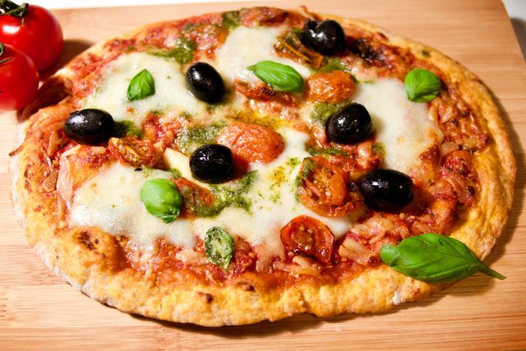 Olives, basil, and mozzarella top a gluten free pizza crust with marinara sauce.